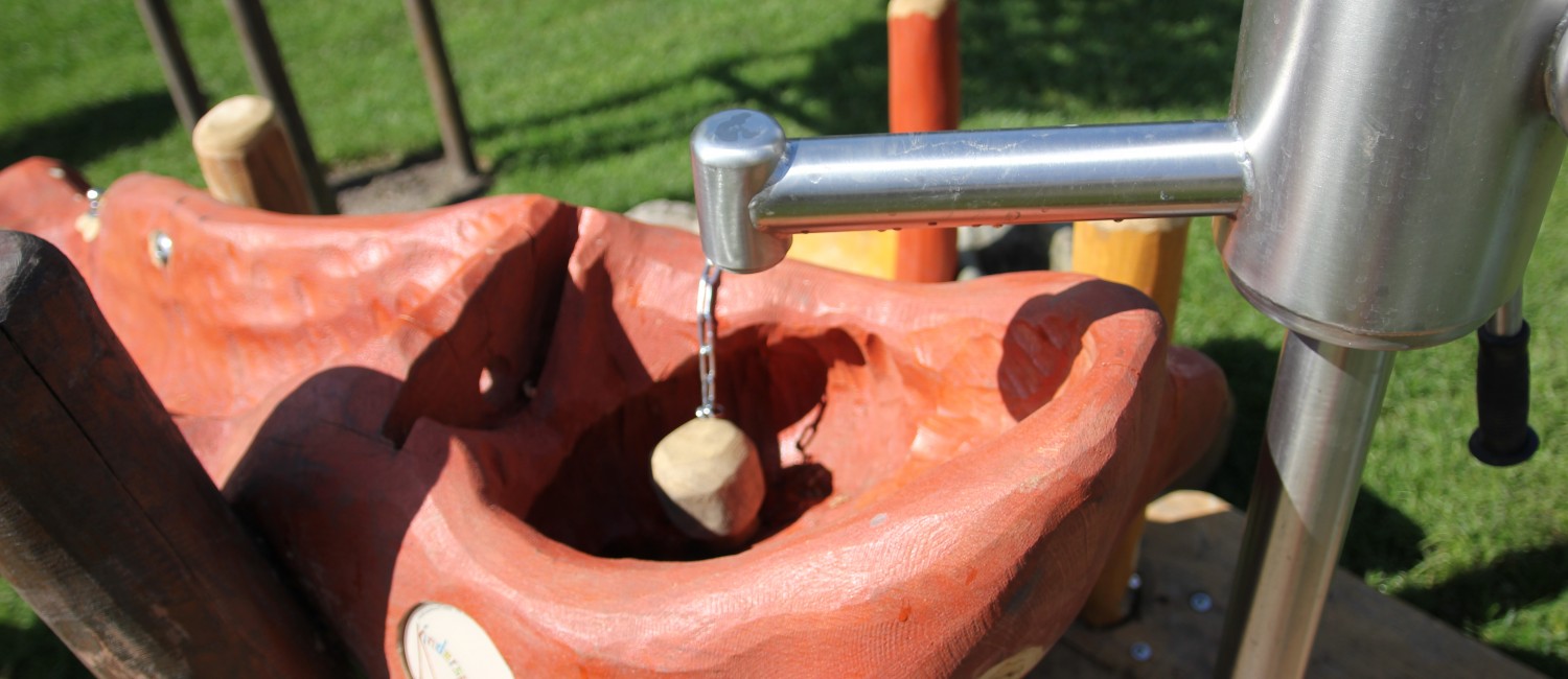 Wasserspielgerät. Pumpe aus der Wasser in einen ausgehöhlten rot lackierten Stamm fließt.